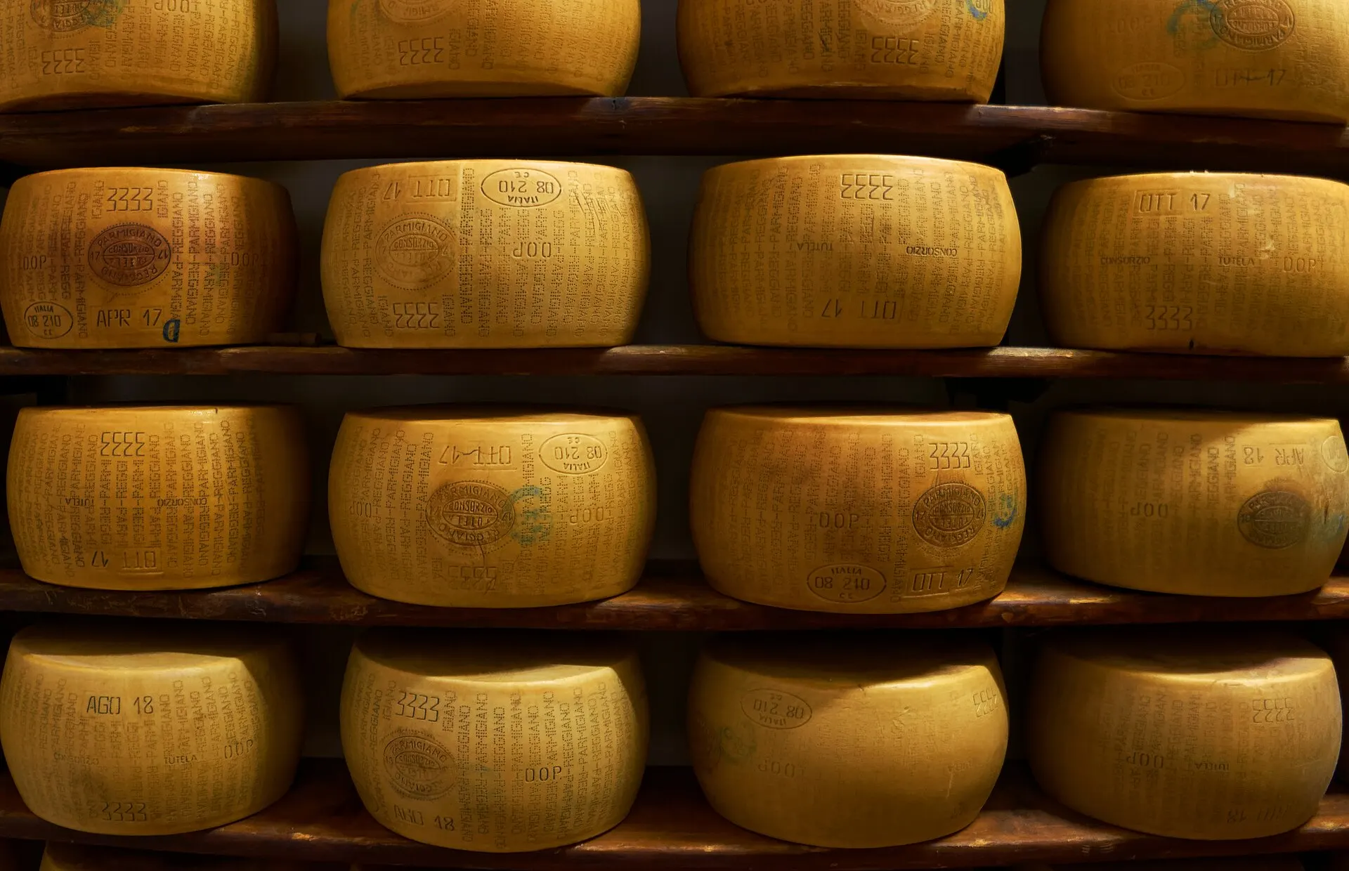 Forme di Parmigiano Reggiano allineate sugli scaffali di stagionatura